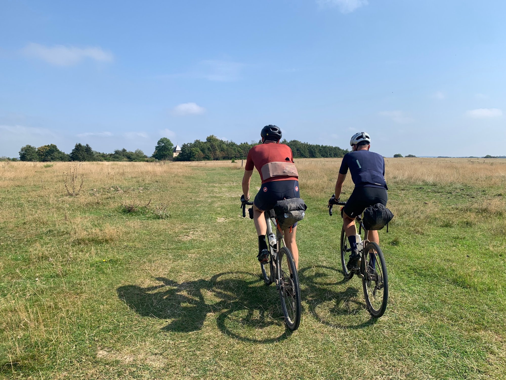 Twee gravelbikers rijden door een weids grasland
