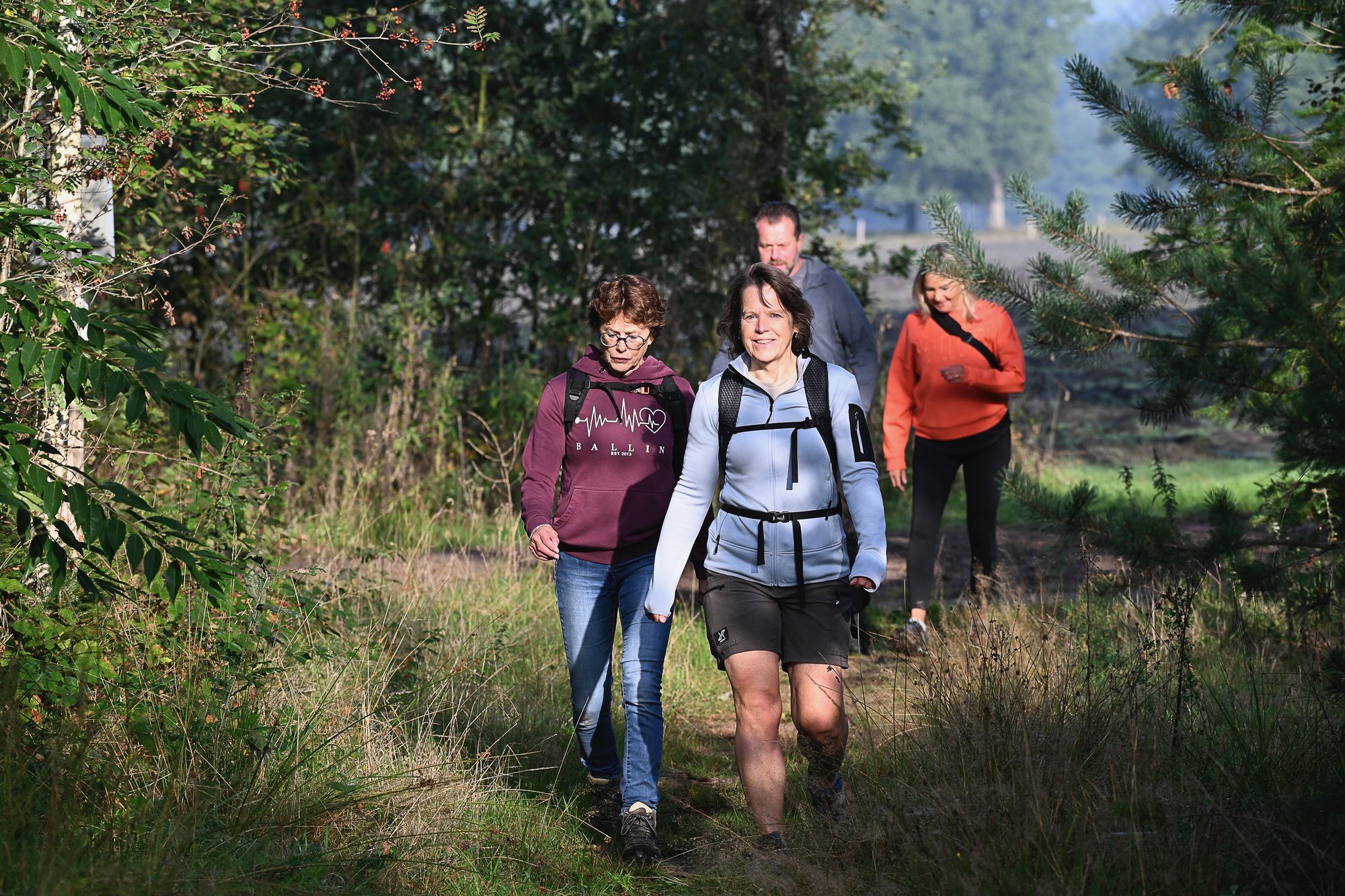 Wandelaars op een bospad in de ochtendzon